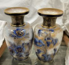 A pair of Doulton Burslem pottery vases decorated with flowers and leaves outlined in gold