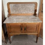 An Edwardian Marble top washstand with a pair of cupboard doors on turned legs