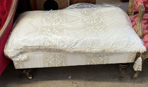 A modern cream upholstered footstool with turned legs and brass casters