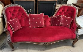 A Victorian walnut framed double chair back settee with plush red button back,