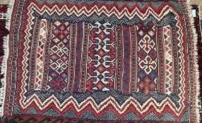 A Kilim rug with a red striped ground to a wave border,