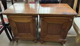 A pair of 20th century bedside cabinets with square tops and single cupboard doors on bun feet