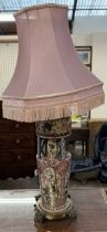 A pottery oil lamp converted to a table lamp on a brass base