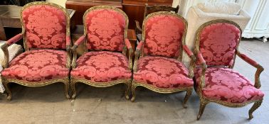 A set of four gilt decorated Continental elbow chairs with damask upholstery with carved rails and
