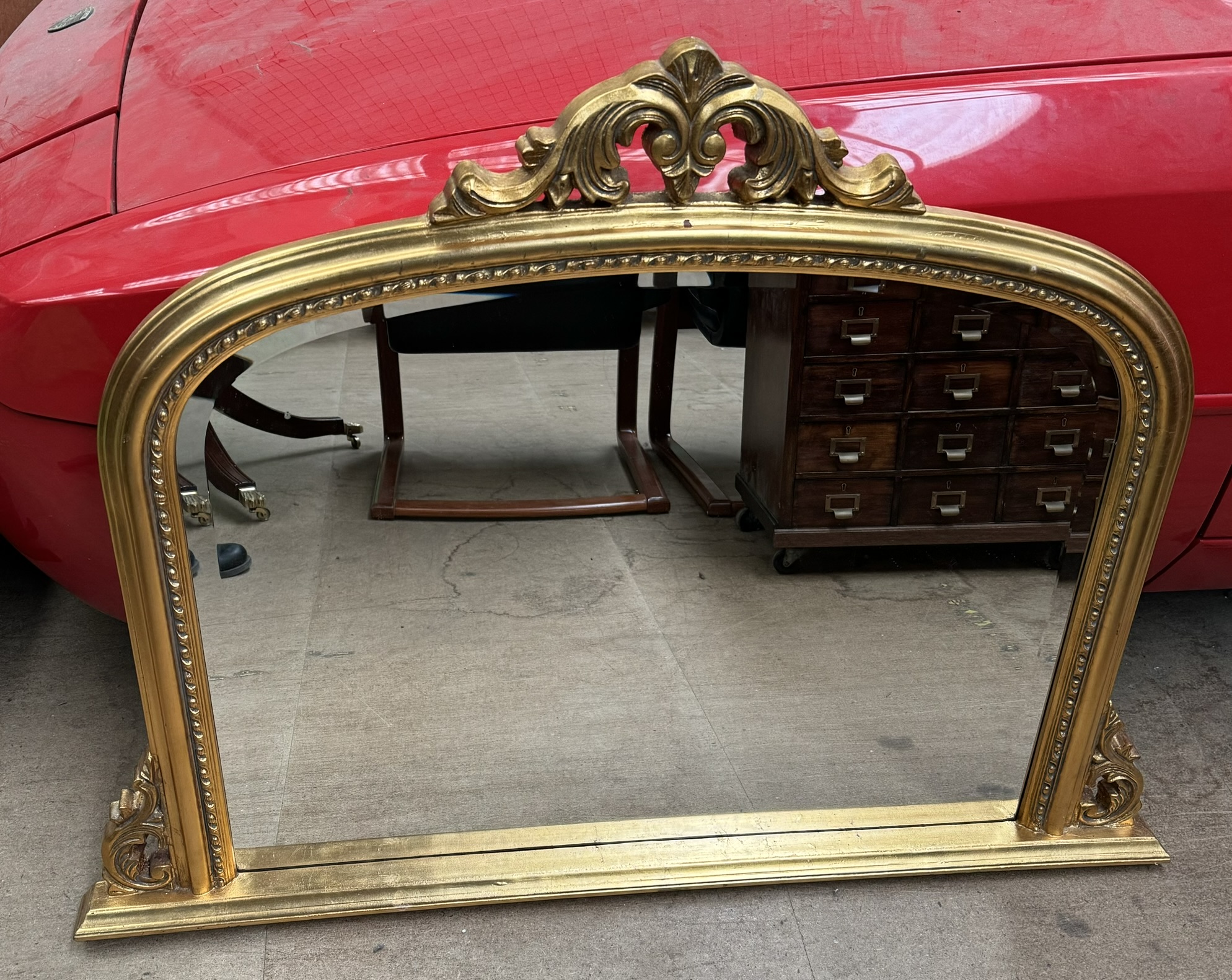 A Victorian style gilt overmantle mirror with a leaf carved cresting rail and scrolling sides
