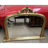 A Victorian style gilt overmantle mirror with a leaf carved cresting rail and scrolling sides