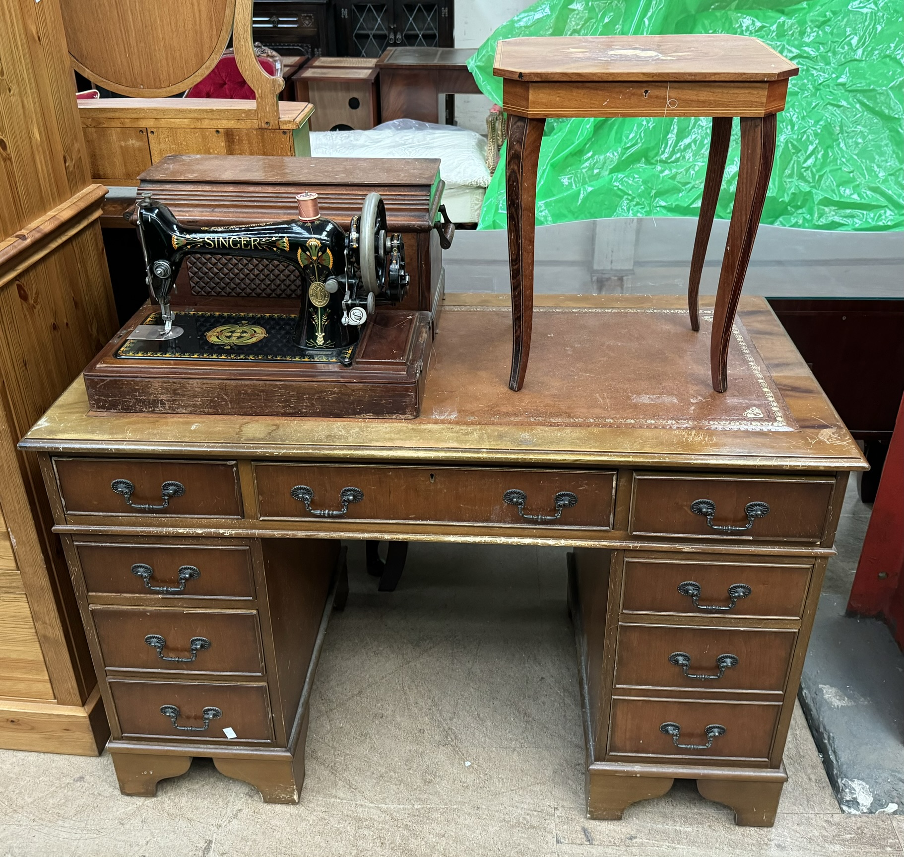 A reproduction yew pedestal desk together with a Singer sewing machine and an inlaid table