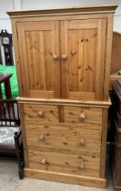 A pine linen cupboard, the top section with a pair of cupboard doors and shelves,