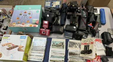 A collection of postcards together with an assortment of cameras etc