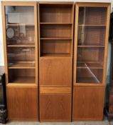 A mid 20th century teak wall unit in three sections with glazed and cupboard doors,