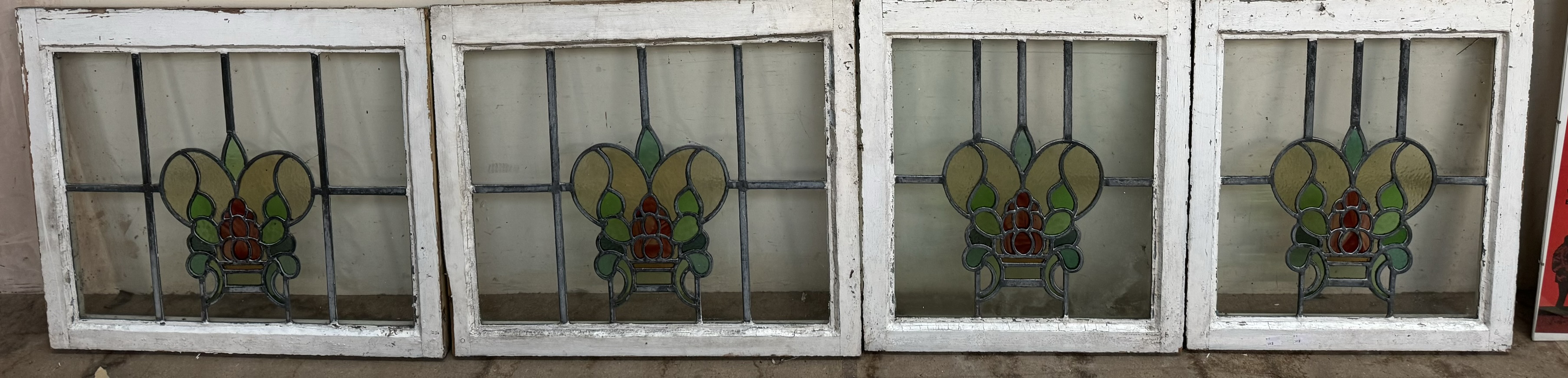 A set of four stained and leaded glass window panels in the form of a vase of flowers