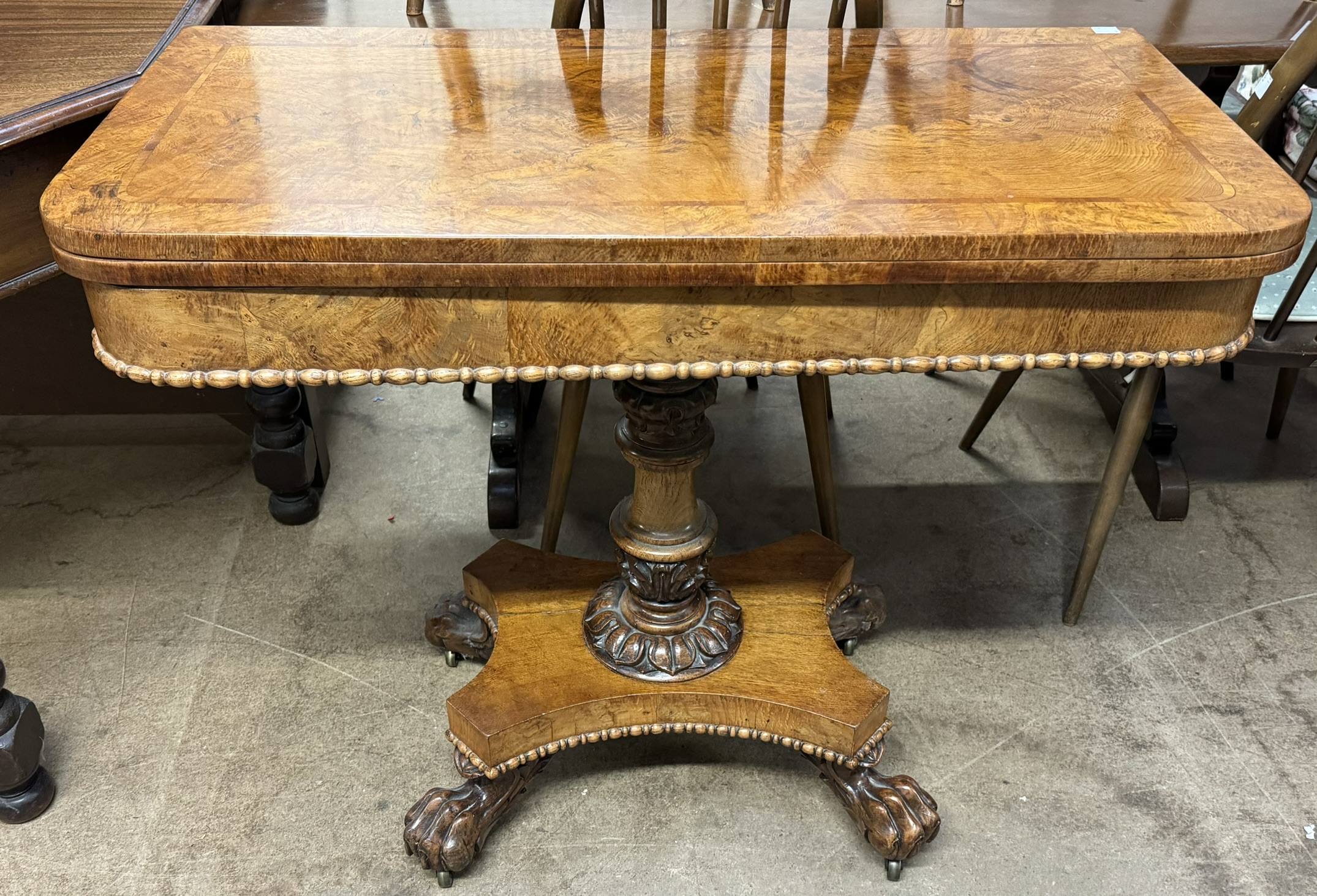 A Victorian oak card table with a crossbanded top above a moulded frieze and fold over baize top on