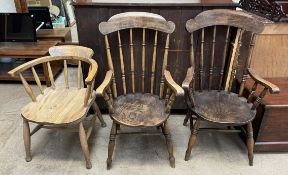A pair of kitchen elbow chairs with turned spindles on a solid seat and turned legs together with a
