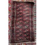 A rug with a red ground with twenty rectangular panels and multiple guard stripes 143 x 80cm