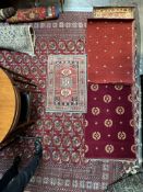 A small rug with a central red ground and geometric decoration to multiple guard stripes,