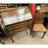 A 20th century walnut bureau with a sloping fall and two drawers on shell capped cabriole legs and