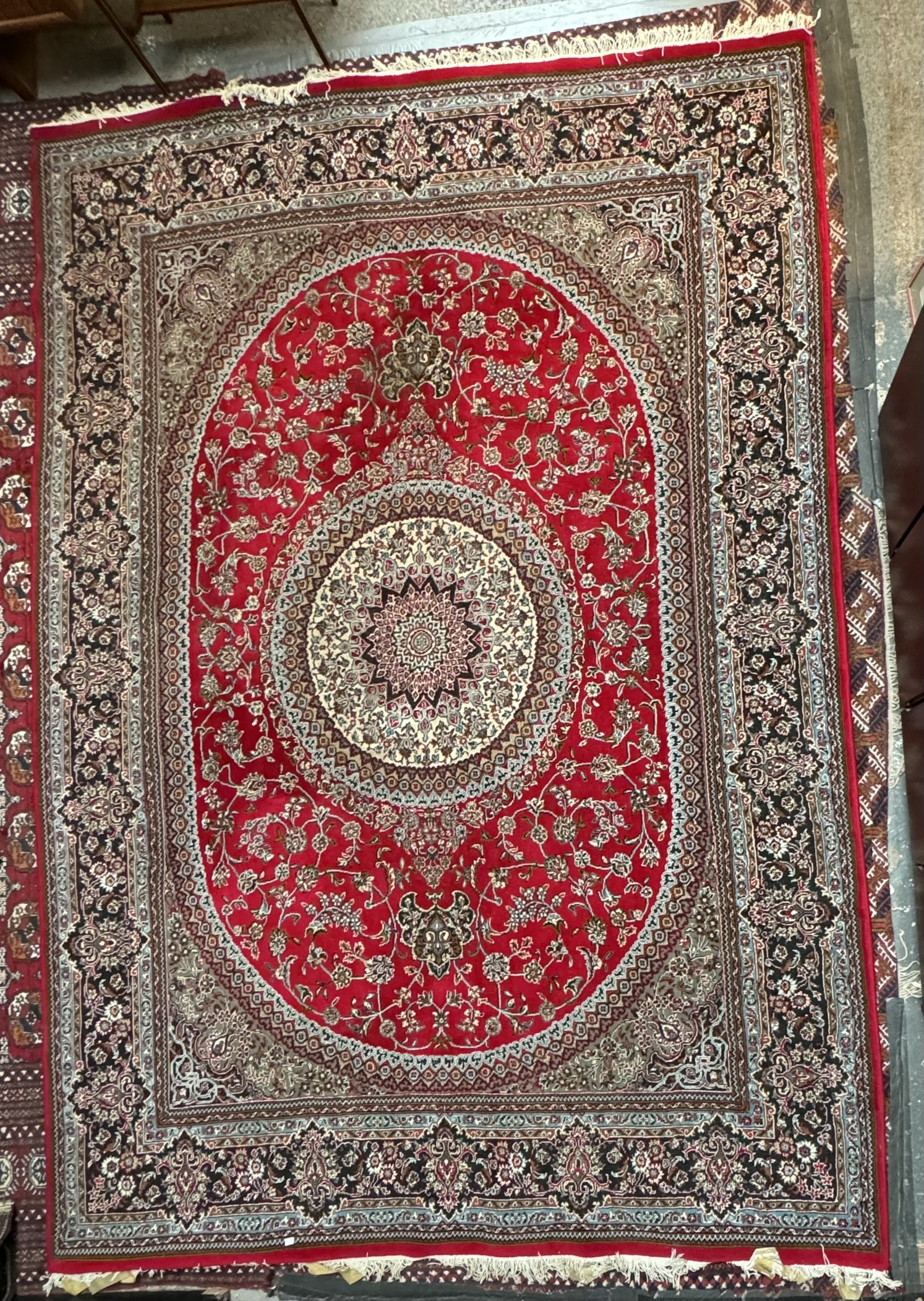 A large Iran rug red ground rug with a radiating pattern of flowers and leaves with multiple guard