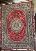A large Iran rug red ground rug with a radiating pattern of flowers and leaves with multiple guard
