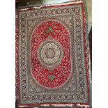 A large Iran rug red ground rug with a radiating pattern of flowers and leaves with multiple guard