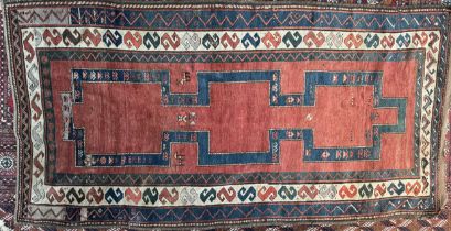 A large rug with a central red ground and a blue internal track with stylised animals to multiple