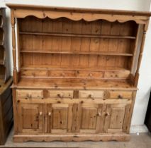 A pine dresser with a canopy above the rack with shelves and drawers,