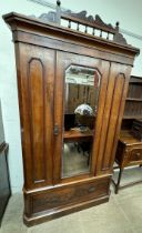 A Victorian mahogany wardrobe with a spindle cresting rail above a mirrored door with a drawer to