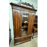 A Victorian mahogany wardrobe with a spindle cresting rail above a mirrored door with a drawer to