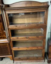 An oak sectional bookcase with an arched three quarter gallery and dentil moulded cornice above