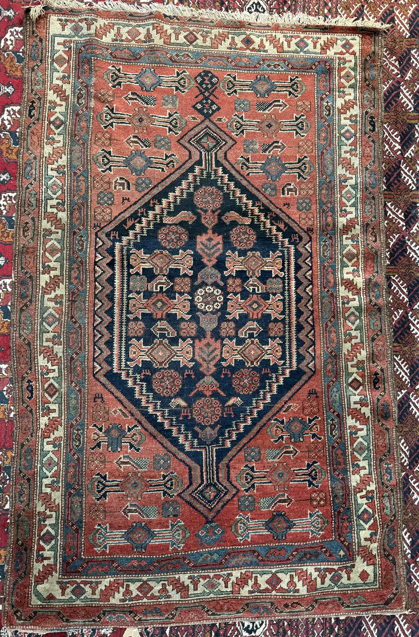 A rug with a red ground the central medallion with a blue ground profusely decorated with stylised