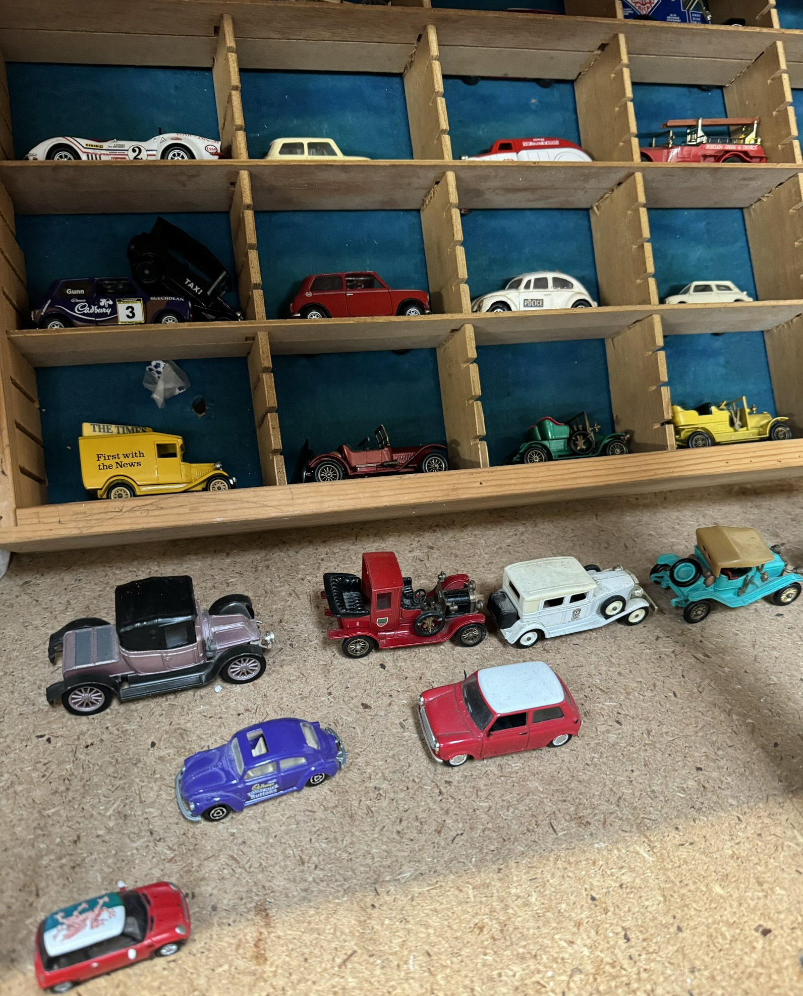 A collection of corgi and other model cars in a sectional shelf unit together with a boxed Corgi