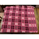 A Welsh blanket with a red ground and geometric patterns