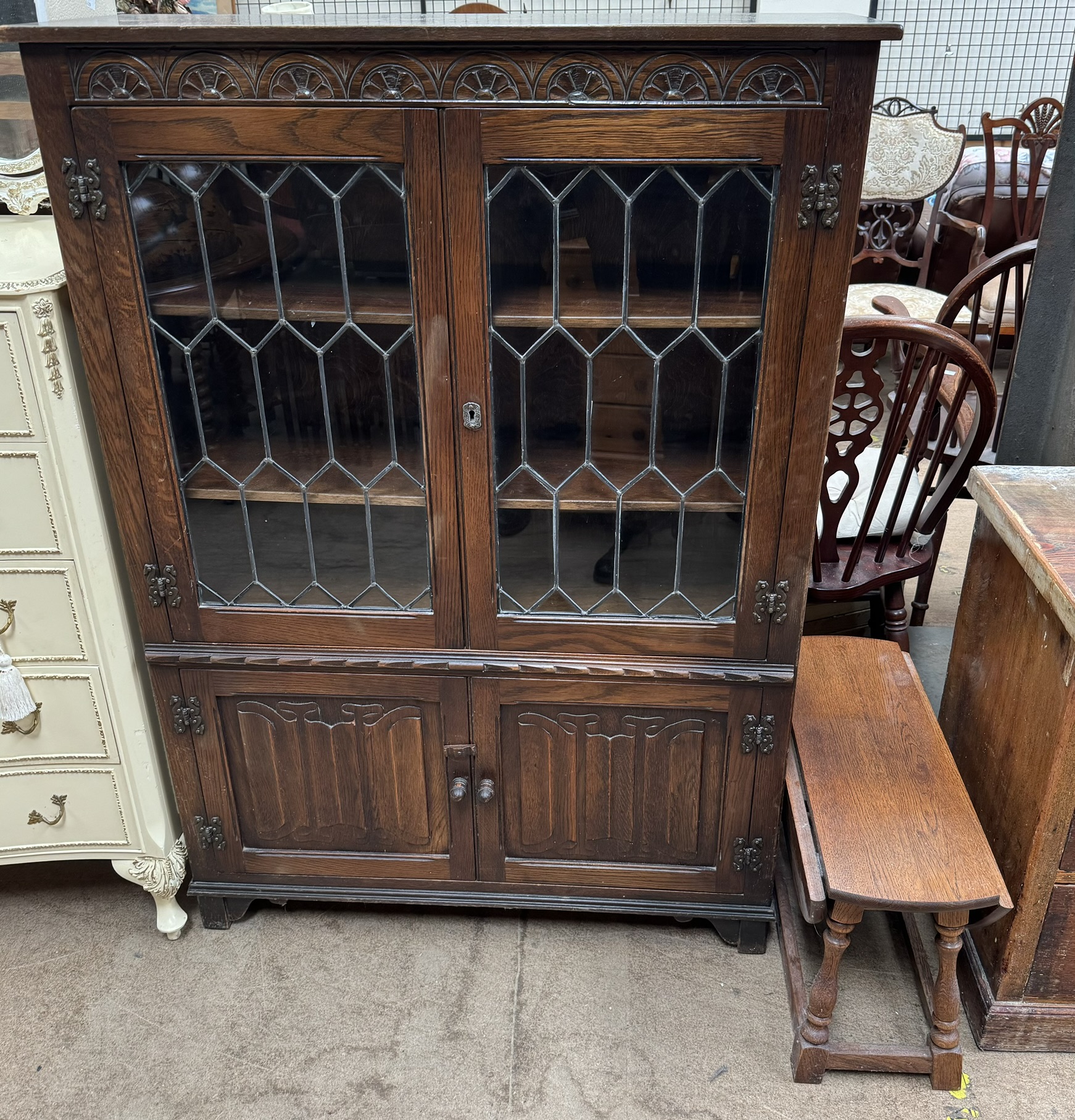 A 20th century oak bookcase with a rectangular top above a carved frieze and leaded glazed doors,