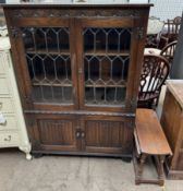 A 20th century oak bookcase with a rectangular top above a carved frieze and leaded glazed doors,