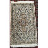 A rug with a cream ground decorated with interlaced flowers and leaves and guard stripes,