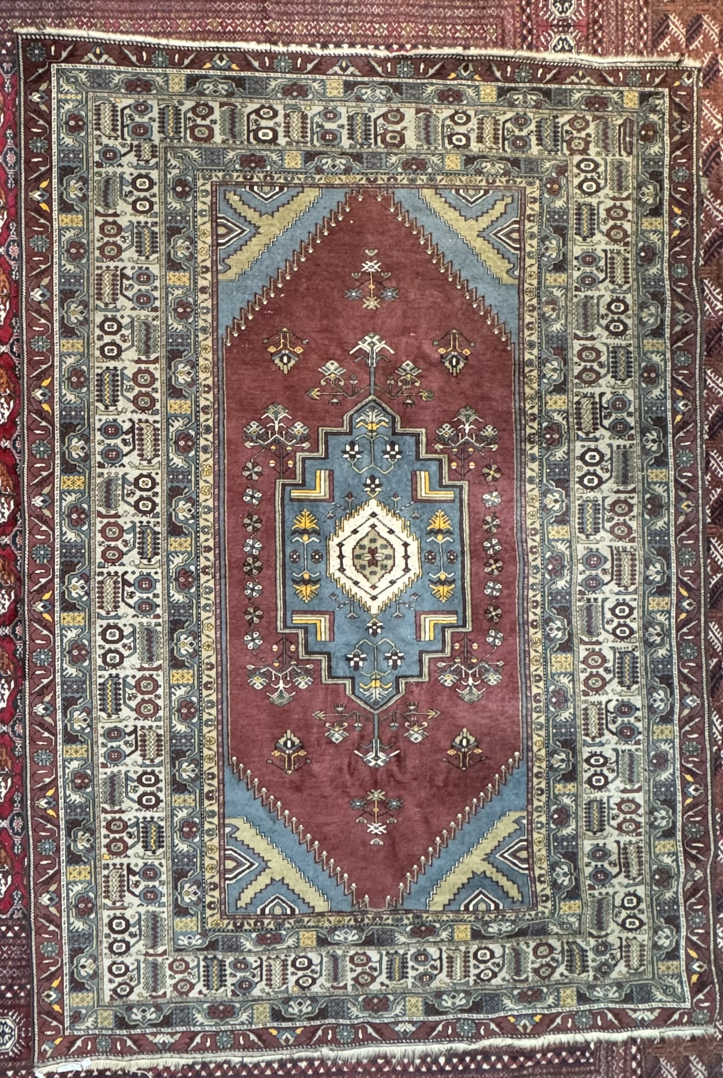 A large rug with a central blue ground medallion within a red field and numerous guard stripes