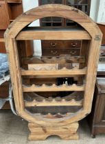 A pine wine rack of oval form with four shelves on a shaped base