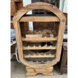 A pine wine rack of oval form with four shelves on a shaped base