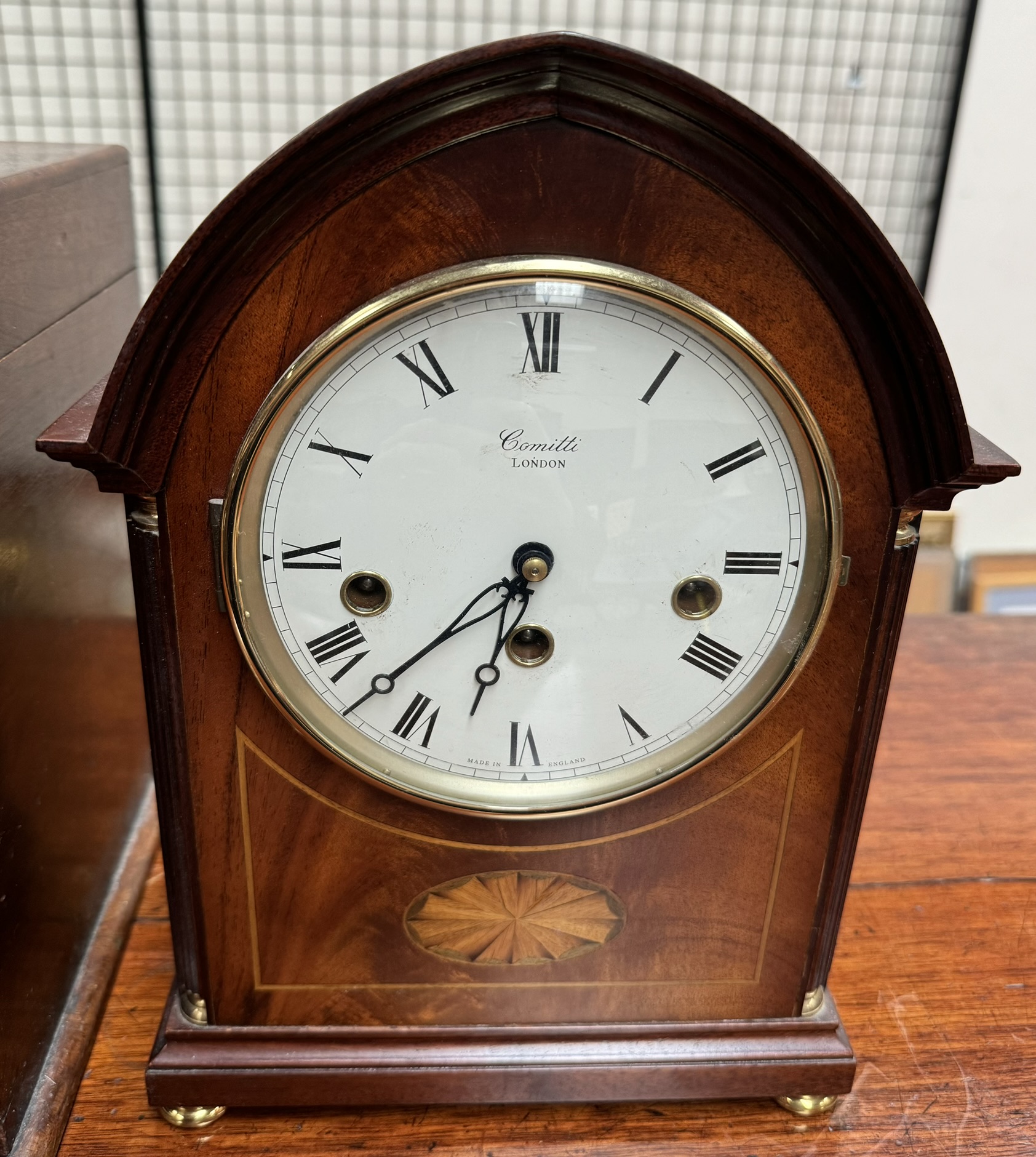 A mahogany mantle clock, of pointed form, inlaid with an oval fan,