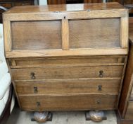 A 20th century oak bureau with a sloping fall and three drawers on flattened bun legs and