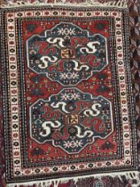 A rug with a red ground and two blue ground medallions decorated with stylised flowerheads and
