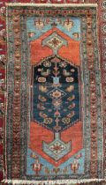 A rug with a central blue medallion with stylised flowerheads,