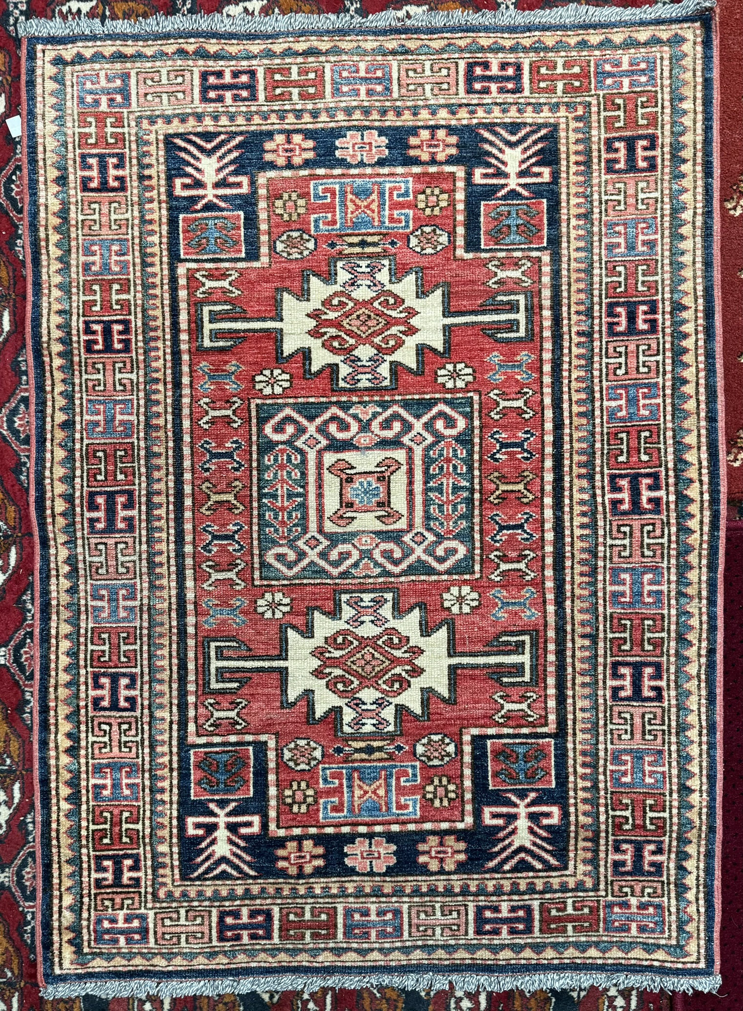 A small rug with a central red ground and geometric decoration to multiple guard stripes, - Image 2 of 2