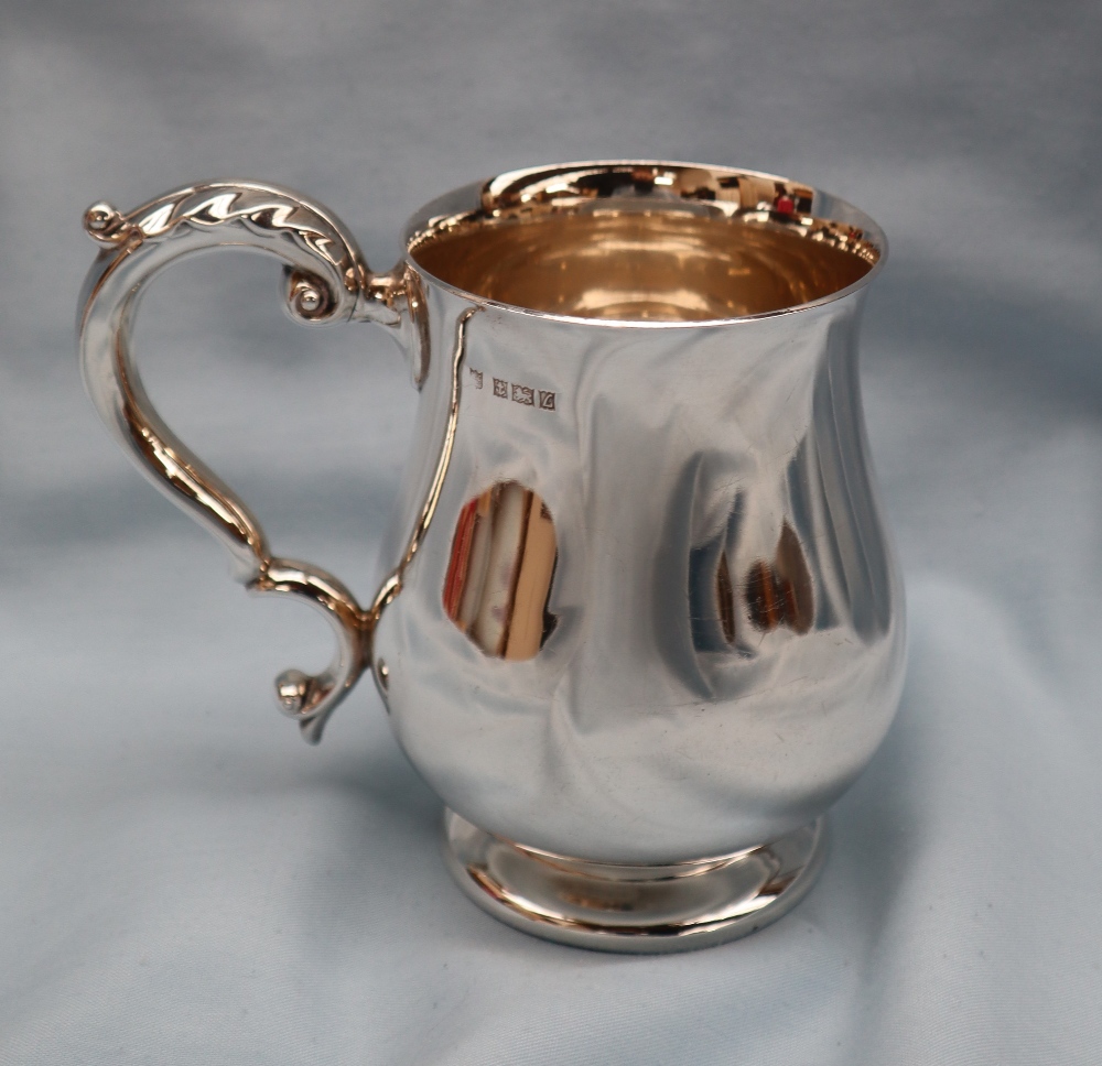 An Elizabeth II silver tankard of baluster form with a leaf capped scrolling handle on a spreading