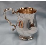 An Elizabeth II silver tankard of baluster form with a leaf capped scrolling handle on a spreading