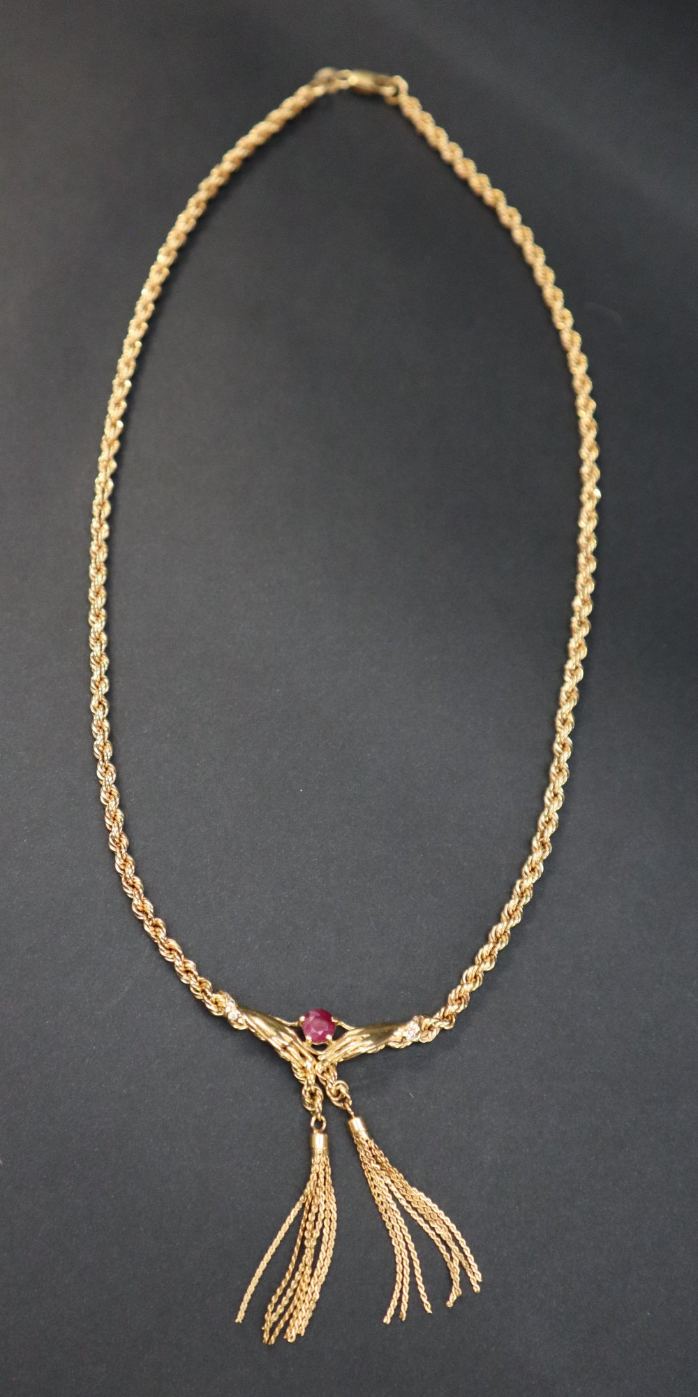 An 18ct yellow gold rope twist necklace, set with a ruby held between hands with tassels underneath, - Image 3 of 4
