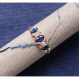 A sapphire and diamond ring set with three oval faceted sapphires and two round old cut diamonds to