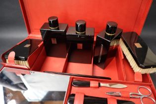 S T Dupont, a red leather travelling case fitted with two brushes, three bottles, easel mirror,