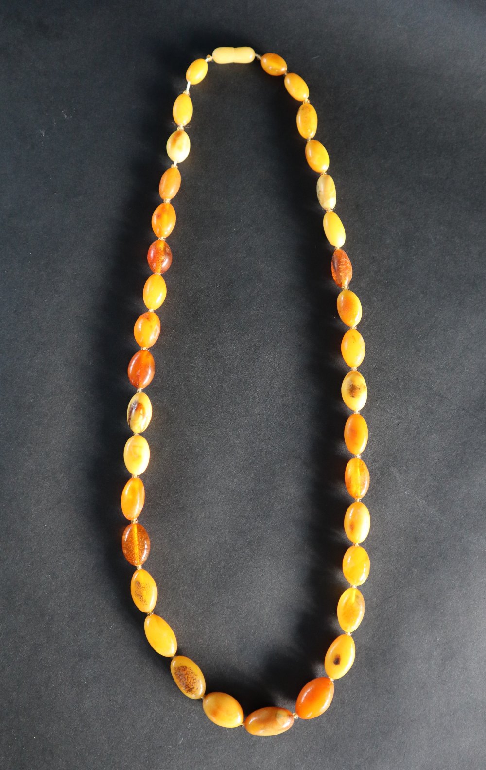 An amber bead necklace, with graduated oval beads, 63cm long, - Image 2 of 3