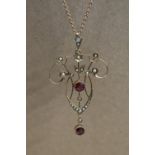 An Edwardian 9ct yellow gold garnet and seed pearl pendant on a 9ct gold chain,