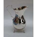 An Edward VII silver cream jug of baluster form with a scrolling handle on four feet, Sheffield,